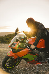 Italy, Elba Island, female motorcyclist against the sun - FBAF00233