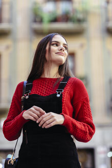 Porträt einer modischen jungen Frau mit rotem Strickpullover und schwarzem Trägerkleid - JSMF00719