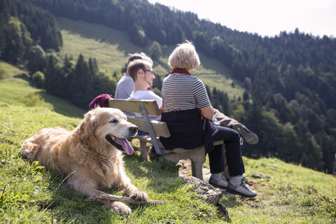 Österreich, Tirol, Kaisergebirge, Wanderer mit Hund rastet auf einer Bank in den Bergen, lizenzfreies Stockfoto