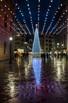 Spanien, Gijon, beleuchteter Weihnachtsbaum in der Fußgängerzone an einem regnerischen Tag am Abend - MGOF03924