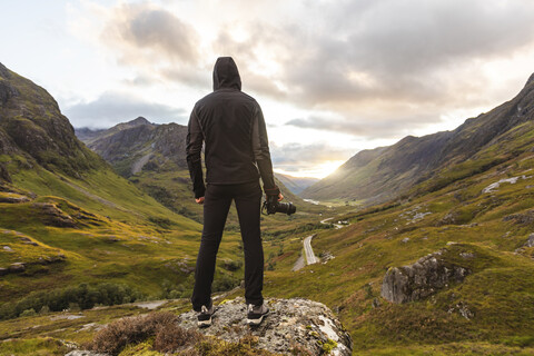 UK, Scotland, Man looking at view with the Three Sisters of Glencoe mountains on the left and the A82 road in the middle of the valley stock photo