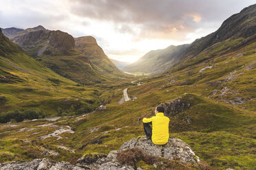 Vereinigtes Königreich, Schottland, Mann mit Blick auf die Three Sisters of Glencoe auf der linken Seite und die Straße A82 in der Mitte des Tals - WPEF01229