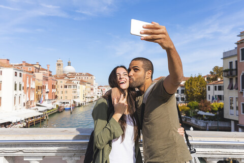 Italien, Venedig, glückliches junges Paar auf einer Brücke, das ein Selfie macht, lizenzfreies Stockfoto