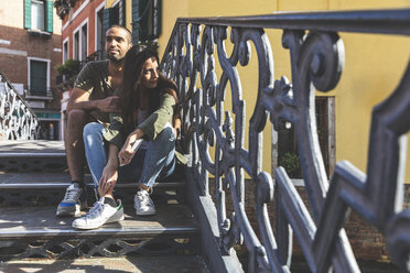 Italien, Venedig, zärtliches junges Paar sitzt auf einer Treppe in der Stadt - WPEF01235
