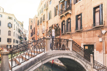 Italien, Venedig, junges Paar steht auf einer kleinen Brücke und erkundet die Stadt - WPEF01248