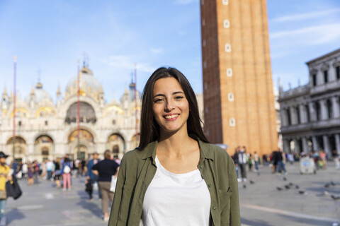 Italien, Venedig, Porträt einer lächelnden jungen Frau auf dem Markusplatz, lizenzfreies Stockfoto