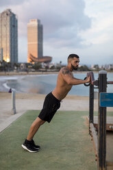 Muskulöser Mann mit nacktem Oberkörper beim Workout am Strand - MAUF02211