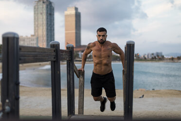 Muskulöser Mann mit nacktem Oberkörper beim Workout am Strand - MAUF02214