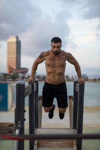 Muskulöser Mann mit nacktem Oberkörper beim Workout am Strand, lizenzfreies Stockfoto