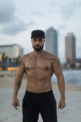Porträt eines muskulösen Mannes mit nacktem Oberkörper im Freien in der Dämmerung - MAUF02233