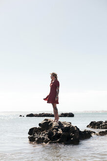 Spanien, Mallorca, tätowierte junge Frau steht auf einem Felsen und schaut in die Ferne - LOTF00020