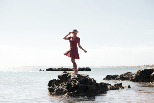 Spain, Mallorca, tattooed young woman standing on a rock looking at distance - LOTF00021