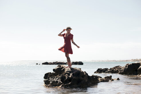 Spanien, Mallorca, tätowierte junge Frau steht auf einem Felsen und schaut in die Ferne - LOTF00021