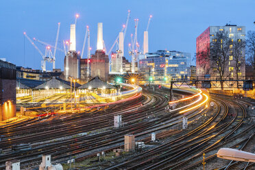 Vereinigtes Königreich, England, London, Blick auf Eisenbahnschienen und Züge am Abend, im Hintergrund das ehemalige Kraftwerk Battersea und Kräne - WPEF01264