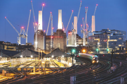 Vereinigtes Königreich, England, London, Blick auf Eisenbahnschienen und Züge am Abend, im Hintergrund das ehemalige Kraftwerk Battersea und Kräne - WPEF01265