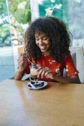 Porträt einer glücklichen jungen Frau beim Kaffeetrinken in einem Café - KIJF02134