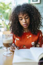 Porträt einer jungen Frau in einem Café, die ein Buch liest - KIJF02137