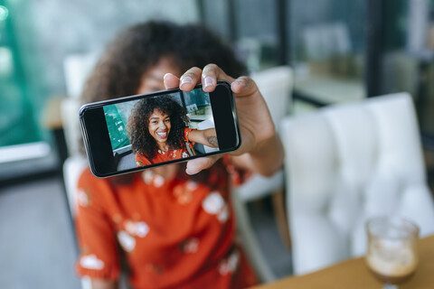 Smiling young woman taking selfie with smartphone, close-up stock photo