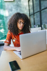 Portrait of serious young woman using laptop in a coffee shop - KIJF02150
