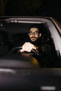 Porträt eines selbstbewussten Mannes am Steuer eines Autos bei Nacht - JRFF02319