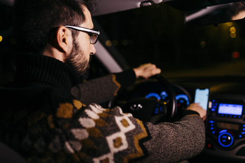 Man using cell phone with road maps in the car at night stock photo