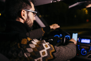 Man using cell phone with road maps in the car at night - JRFF02321