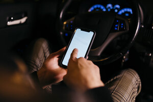 Mann, der nachts im Auto sein Mobiltelefon benutzt - JRFF02323