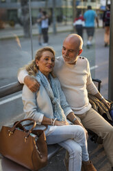 Spanien, Barcelona, älteres Paar mit Gepäck an der Straßenbahnhaltestelle in der Stadt sitzend - MAUF02239