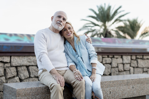 Spain, Barcelona, happy senior couple embracing on a bench stock photo