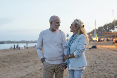 Spanien, Barcelona, glückliches älteres Paar am Strand in der Abenddämmerung - MAUF02264