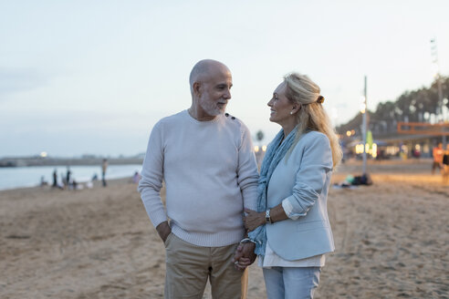 Spanien, Barcelona, glückliches älteres Paar am Strand in der Abenddämmerung - MAUF02264