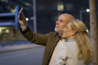 Spanien, Barcelona, glückliches älteres Paar, das ein Selfie in der Stadt in der Abenddämmerung macht - MAUF02269