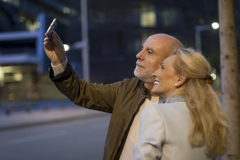 Spanien, Barcelona, glückliches älteres Paar, das ein Selfie in der Stadt in der Abenddämmerung macht - MAUF02269