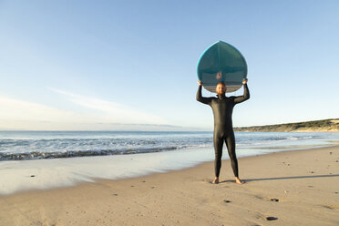 Spanien, Andalusien, Tarifa, Porträt eines Mannes mit Stand Up Paddle Board am Strand - KBF00364