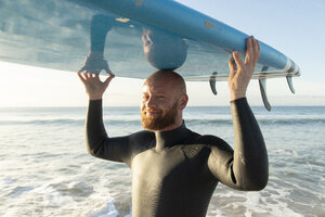 Spanien, Andalusien, Tarifa, Porträt eines lächelnden Mannes mit Stand Up Paddle Board am Meer - KBF00366