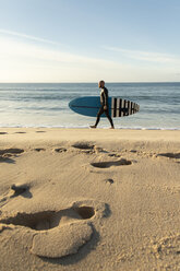 Spanien, Andalusien, Tarifa, Mann zu Fuß mit Stand Up Paddle Board am Strand - KBF00368