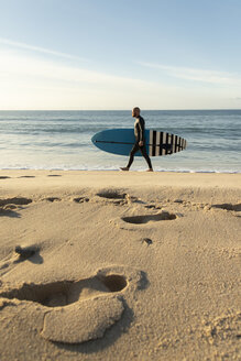 Spanien, Andalusien, Tarifa, Mann zu Fuß mit Stand Up Paddle Board am Strand - KBF00368