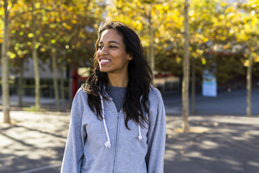 Portrait of a smiling woman, standing in a park - GIOF05300