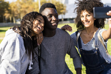 Three friends spending time in the city, taking selfies with a smartphone - GIOF05314