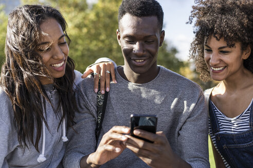 Drei Freunde verbringen Zeit in der Stadt und benutzen ihr Smartphone - GIOF05317