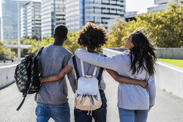 Drei Freunde erkunden die Stadt, gehen Arm in Arm die Straße entlang - GIOF05319