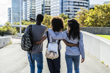 Three friends exploring the city, walking down the street, arm in arm - GIOF05321