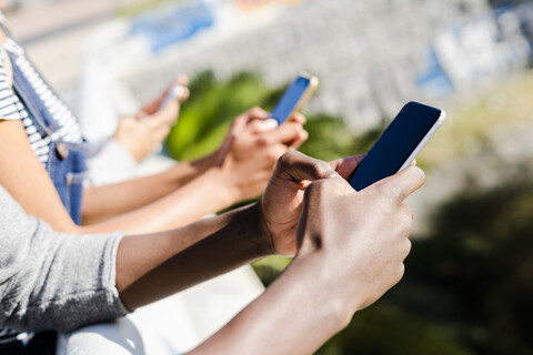 Freunde, die nebeneinander stehen und Smartphones benutzen, lizenzfreies Stockfoto