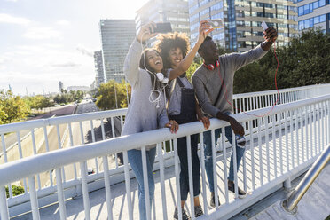 Freunde stehen auf einer Brücke und machen Selfies - GIOF05344