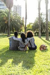 Three friends sitting in a park, watching the sunset - GIOF05431