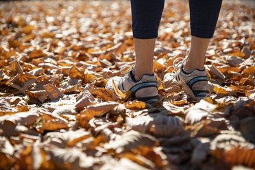 Close-up of spotive woman standing in autumn leaves - CHPF00528