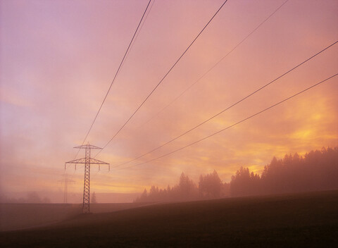 Strommast in dunstiger ländlicher Landschaft, lizenzfreies Stockfoto