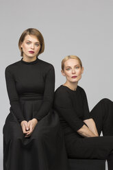 Studio portrait of mother and adult daughter sitting down - VGF00161