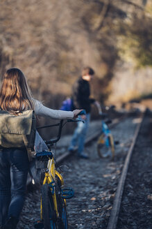 Junge und Mädchen gehen mit Fahrrädern auf der Bahnstrecke - OCMF00190