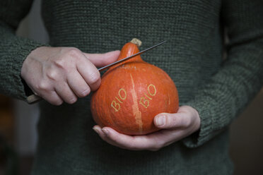 Woman's hands cutting organic Hokkaido pumpkin with Smart Branding - MAMF00292